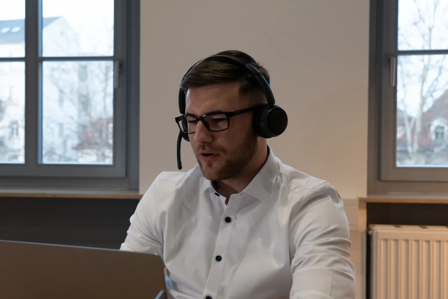 Hannes Henke mit Headset am Laptop im Kundengespräch