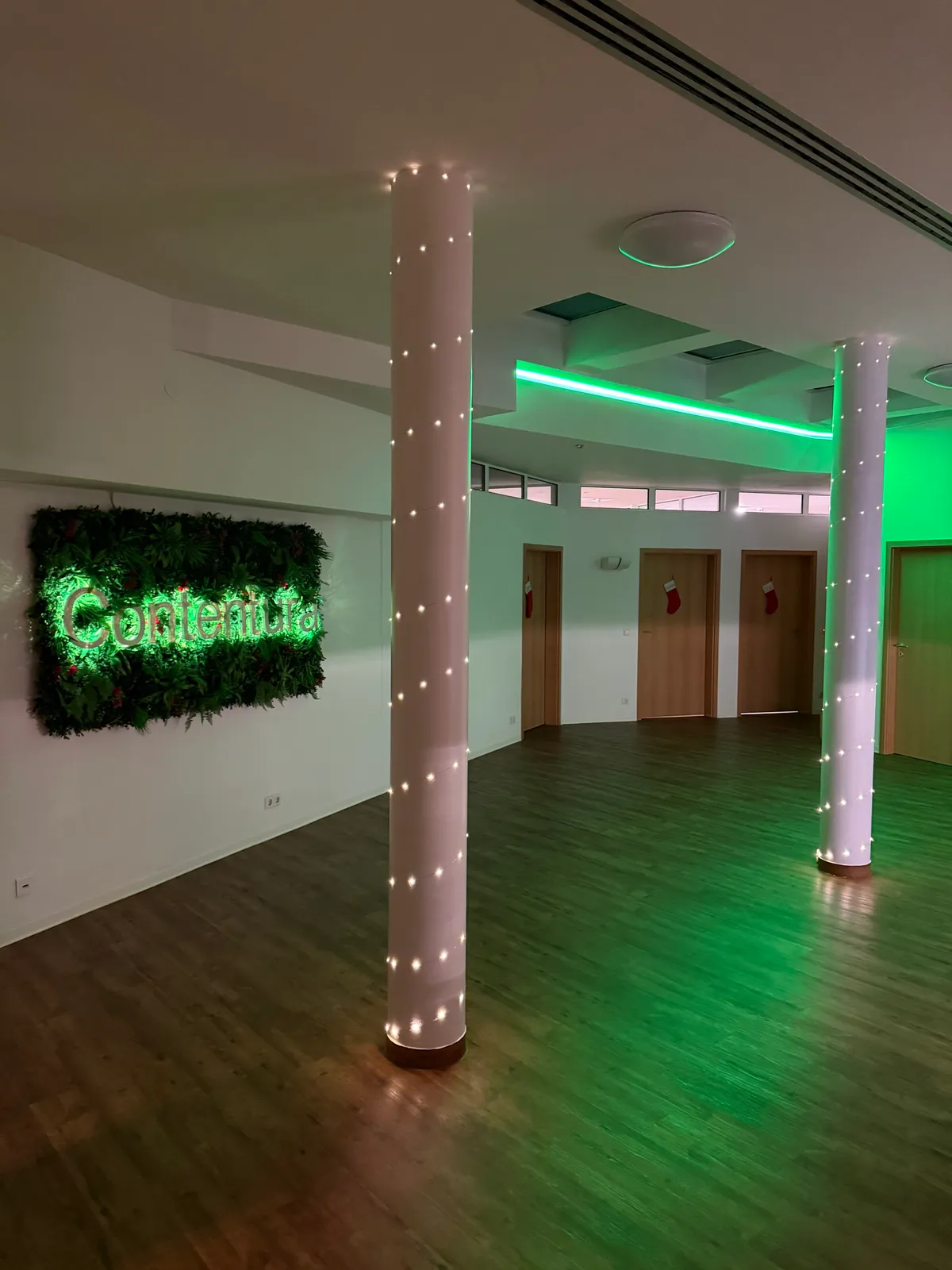 Der Empfangsbereich im Dezember: begrünte Wand mit beleuchtetem Contentura-Schriftzug, Säulen mit Lichterketten